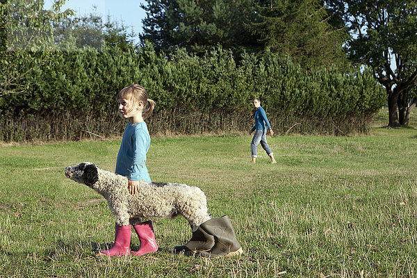 Seitenansicht des Mädchens mit Hund in Gummistiefeln auf dem Feld