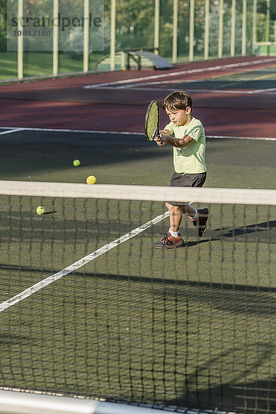 Junge spielt Tennis auf dem Platz