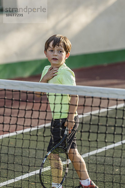 Junge mit Tennisschläger im Stehen auf dem Feld