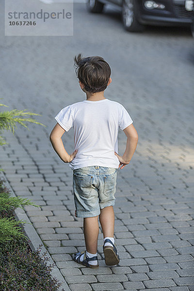 Rückansicht des Jungen mit den Händen auf der Hüfte stehend auf der Straße