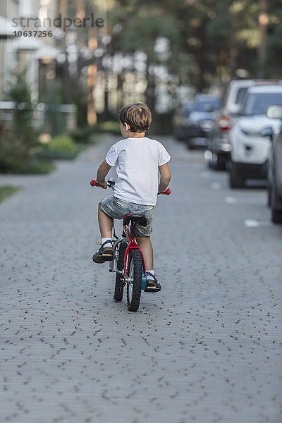 Rückansicht des Jungen beim Fahrradfahren auf der Straße