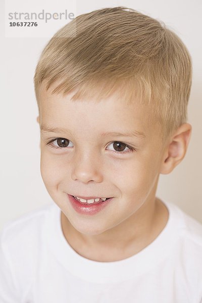 Porträt des lächelnden Jungen vor weißem Hintergrund