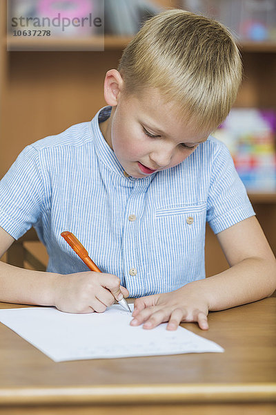 Nahaufnahme des Jungen beim Schreiben auf Papier am Tisch