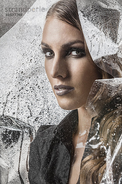 Porträt einer schönen Frau in Plastik gehüllt vor schwarzem Hintergrund