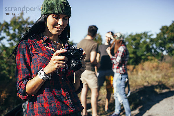 Junge Frau beim Betrachten von Fotografien mit Freunden im Wald
