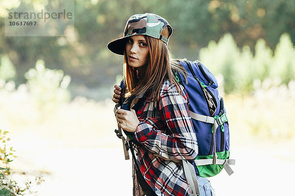 Porträt der modischen jungen Frau beim Wandern im Wald