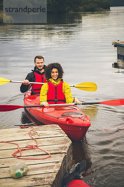 Glücklicher Mann und Frau beim Kajakfahren auf dem See