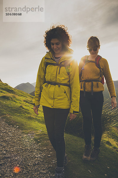 Weibliche Freunde  die bei Sonnenuntergang auf dem Berg gegen den Himmel laufen.