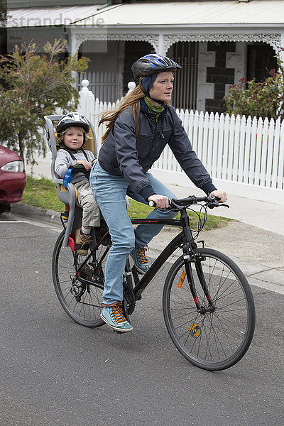 Volle Länge der Mutter beim Radfahren  während der Sohn auf dem Rücksitz sitzt.