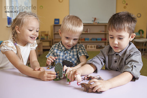 Kinder spielen mit Tierspielzeug am Tisch im Klassenzimmer