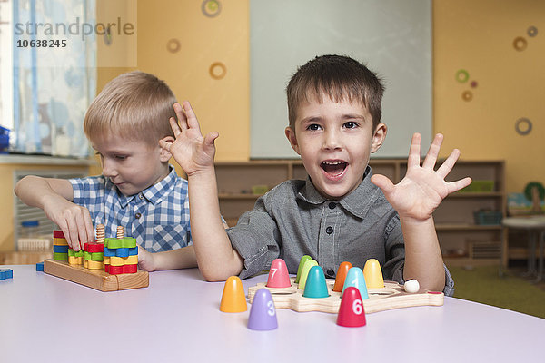 Süße kleine Jungen  die mit Spielzeug am Tisch im Klassenzimmer spielen.