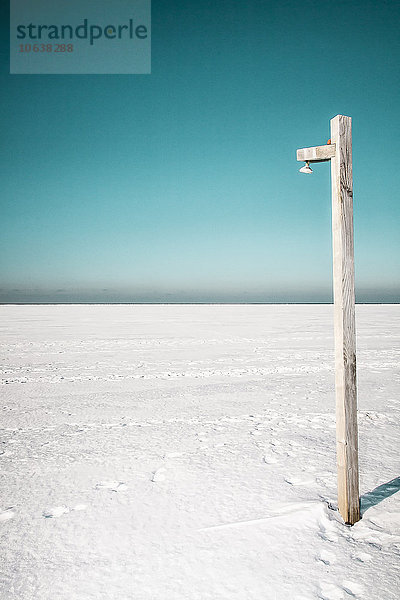 Holzpfosten auf verschneiter Landschaft gegen klaren Himmel