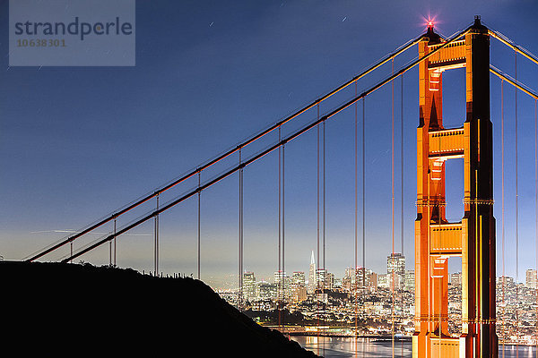 Golden Gate Bridge mit beleuchtetem Stadtbild im Hintergrund