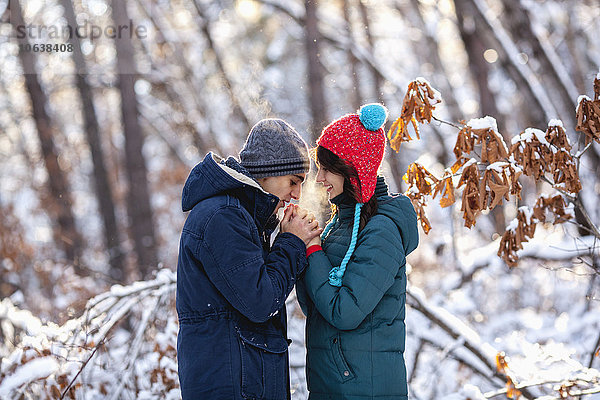 Seitenansicht eines romantischen jungen Paares  das im Winter Händchen hält.