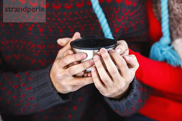 Mittelteil des jungen Paares mit Kaffeetasse im Winter