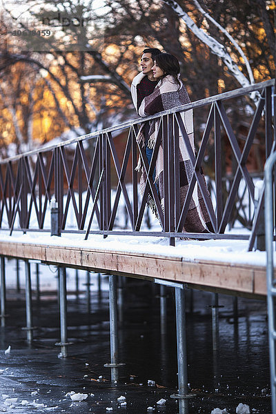 Junges Paar im Winter auf der Brücke in Decke gewickelt