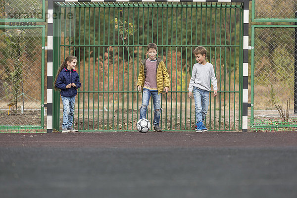Kinder spielen Fußball auf dem Spielplatz