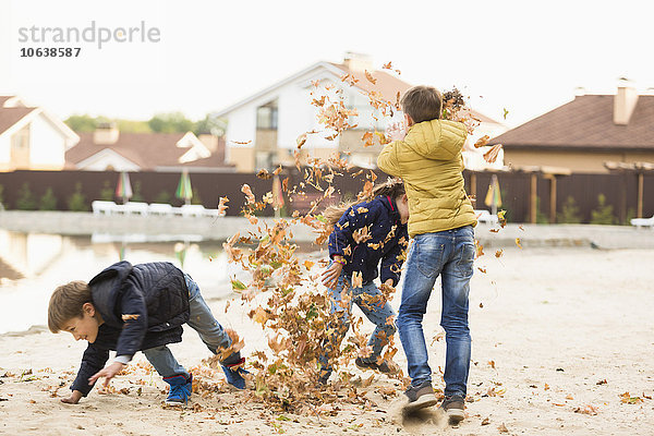 Kinder beim Spielen mit trockenen Blättern auf dem Wanderweg