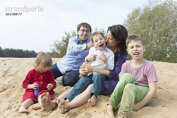 Fröhliche Familie sitzt zusammen auf einer Sanddüne