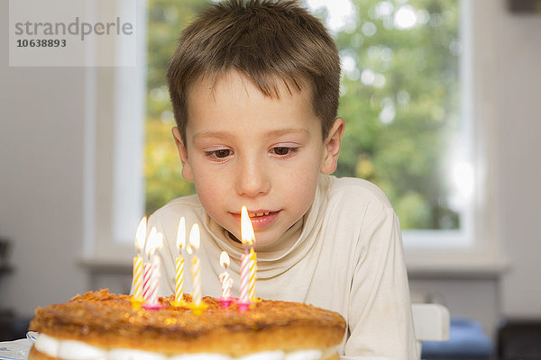 Süßes Geburtstagskind beim Anblick von Kerzen auf Kuchen