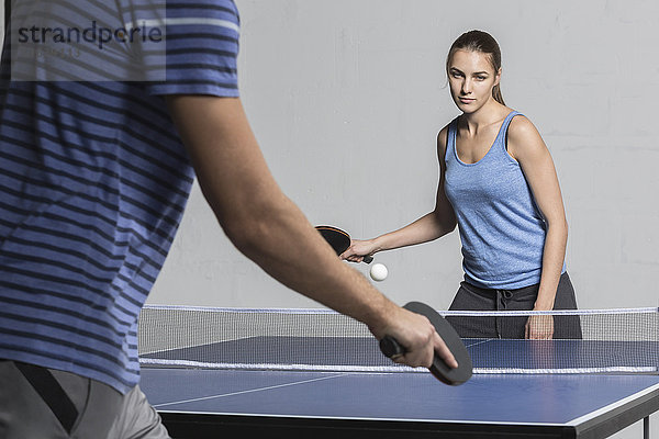 Selbstbewusste junge Frau beim Tischtennisspielen mit Mann