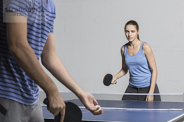 Entschlossene junge Frau beim Tischtennisspielen mit Mann