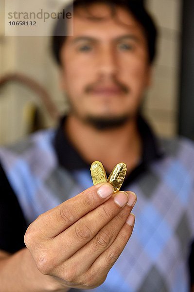 Mann mit zwei Stücken Gold in einem Laden  in dem Gold angekauft wird  Goldgräberstadt Laberinto bei Puerto Maldonado  Departamento Madre de Dios  Peru  Südamerika