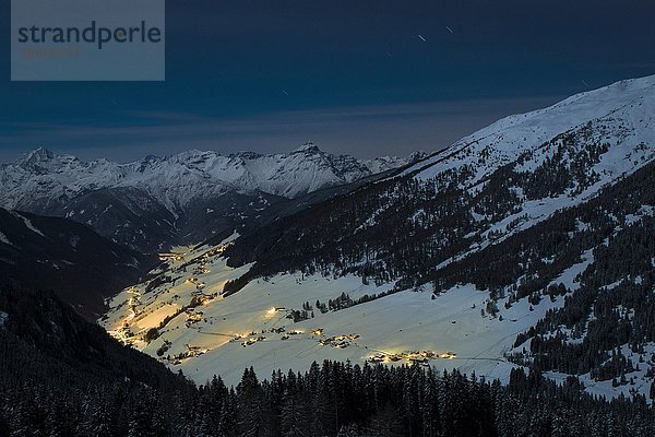 Beleuchtetes Bergdorf im Winter bei Dämmerung  hinten Stubaier Alpen  Navis  Wipptal  Tirol  Österreich  Europa
