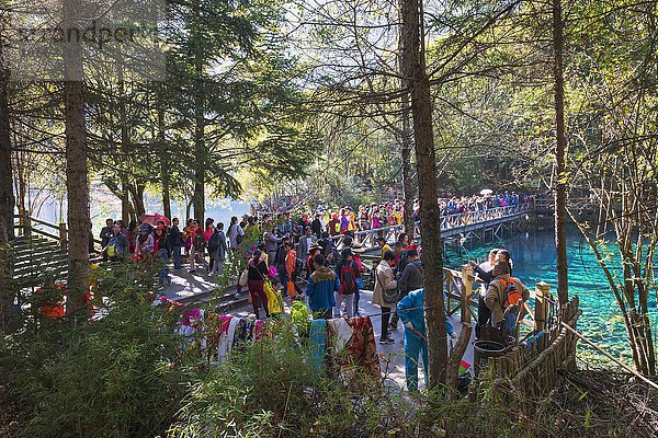 Menschenmenge auf einer Fußgängerbrücke über den Colorful Lake  Jiuzhaigou-Nationalpark  Provinz Sichuan  China  Asien