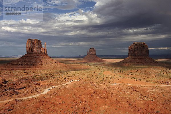 Felsformationen  West Mitten Butte  East Mitten Butte und Merrick Butte  vorne Valley Drive  nach einem Gewitter  Gewitterwolken  Abendlicht  Monument Valley Navajo Tribal Park  Arizona  USA  Nordamerika