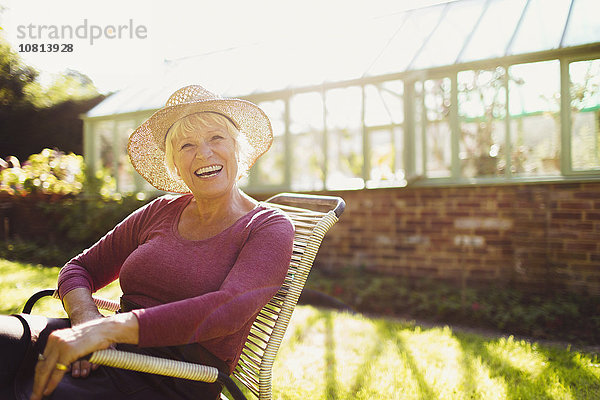 Portrait begeisterte Seniorin sitzt vor einem sonnigen Gewächshaus