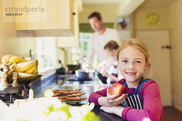 Portrait lächelndes Mädchen beim Apfelessen in der Küche