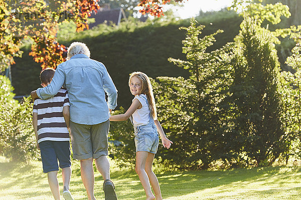 Portrait lächelndes Mädchen beim Spaziergang mit Großmutter und Bruder im Garten