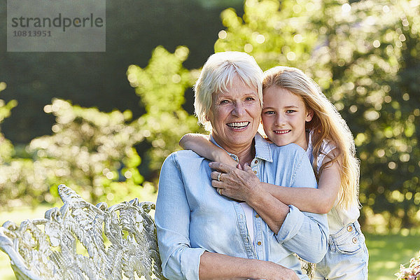 Portrait lächelnde Großmutter und Enkelin umarmend im Garten
