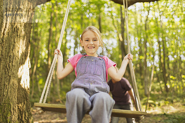 Portrait lächelndes Mädchen am Seil schwingend im Wald