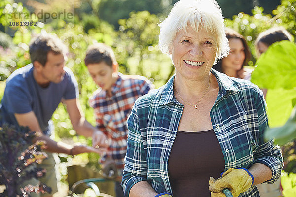 Portrait lächelnde Seniorin im sonnigen Garten mit Familie