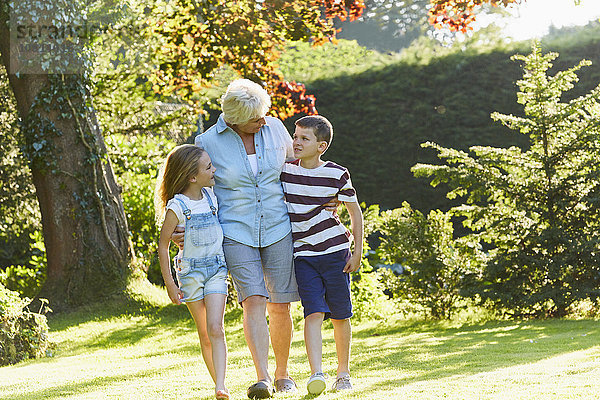 Großmutter und Enkelkinder wandern im sonnigen Garten