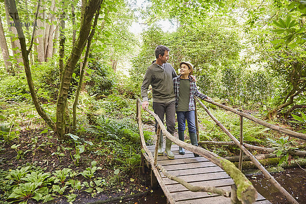 Vater und Sohn überqueren Fußgängerbrücke im Wald