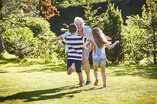 Enkelkinder rennen zur Großmutter im sonnigen Garten