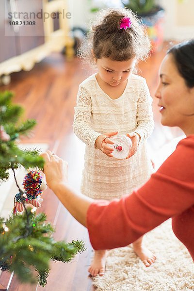 Mutter und Tochter schmücken den Weihnachtsbaum