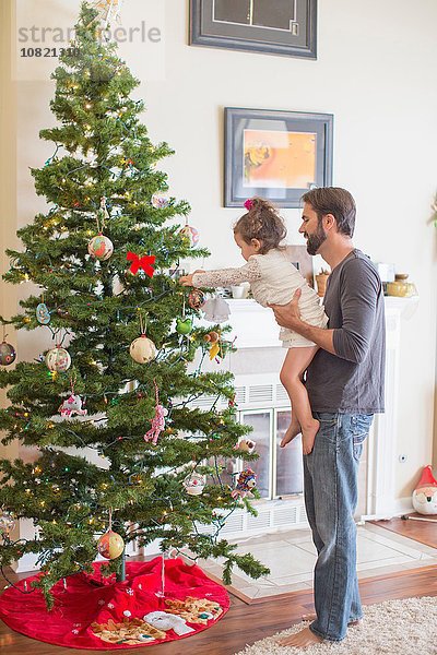 Vater und Tochter schmücken den Weihnachtsbaum