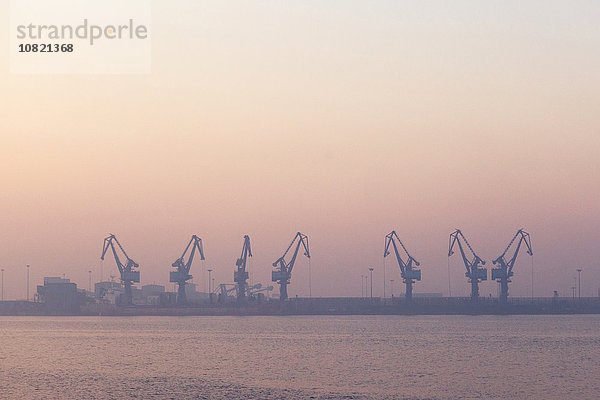 Kräne im Hafen bei Sonnenaufgang