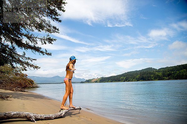 Junge Frau im Bikini auf Baumzweig am Strand  Nehalem Bay  Oregon  USA