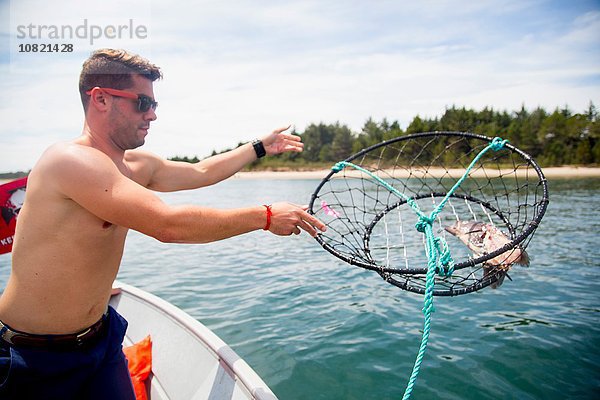 Mittlerer Erwachsener Mann  der eine Köderfalle vom Fischerboot wirft  Nehalem Bay  Oregon  USA