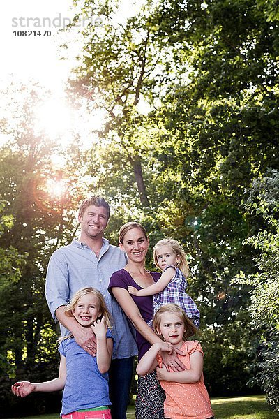 Porträt von Eltern und drei jungen Töchtern im sonnenbeschienenen Park