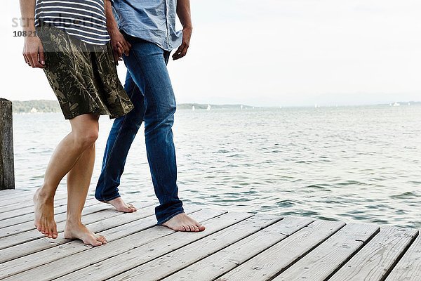 Ausschnitt eines romantischen Paares beim Spaziergang am Holzsteg  Starnberger See  Bayern  Deutschland
