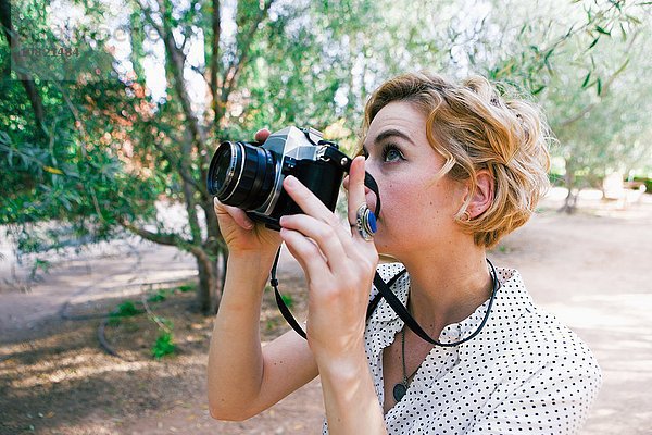 Mittlere erwachsene Frau beim Fotografieren im Park