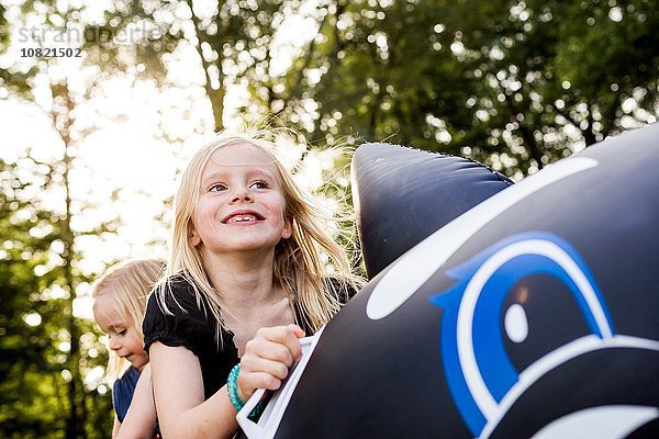 Zwei Schwestern spielen auf dem aufblasbaren Wal im Park