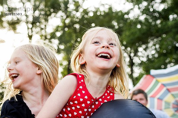 Zwei junge Schwestern beim Spielen auf Hüpfburgen im Park