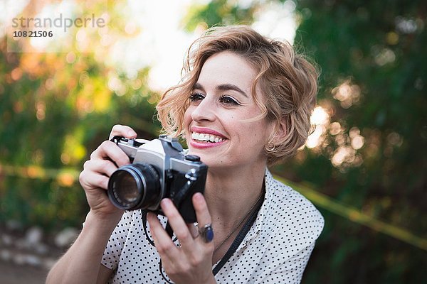 Mittlere erwachsene Frau beim Fotografieren  draußen  lächelnd
